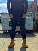 Person wearing dark pants and yellow boots standing on a concrete surface with industrial equipment in the background.
