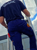 Electrician wearing DFP Workwear PP3 stretch canvas work pants while working on a ladder at a construction site.