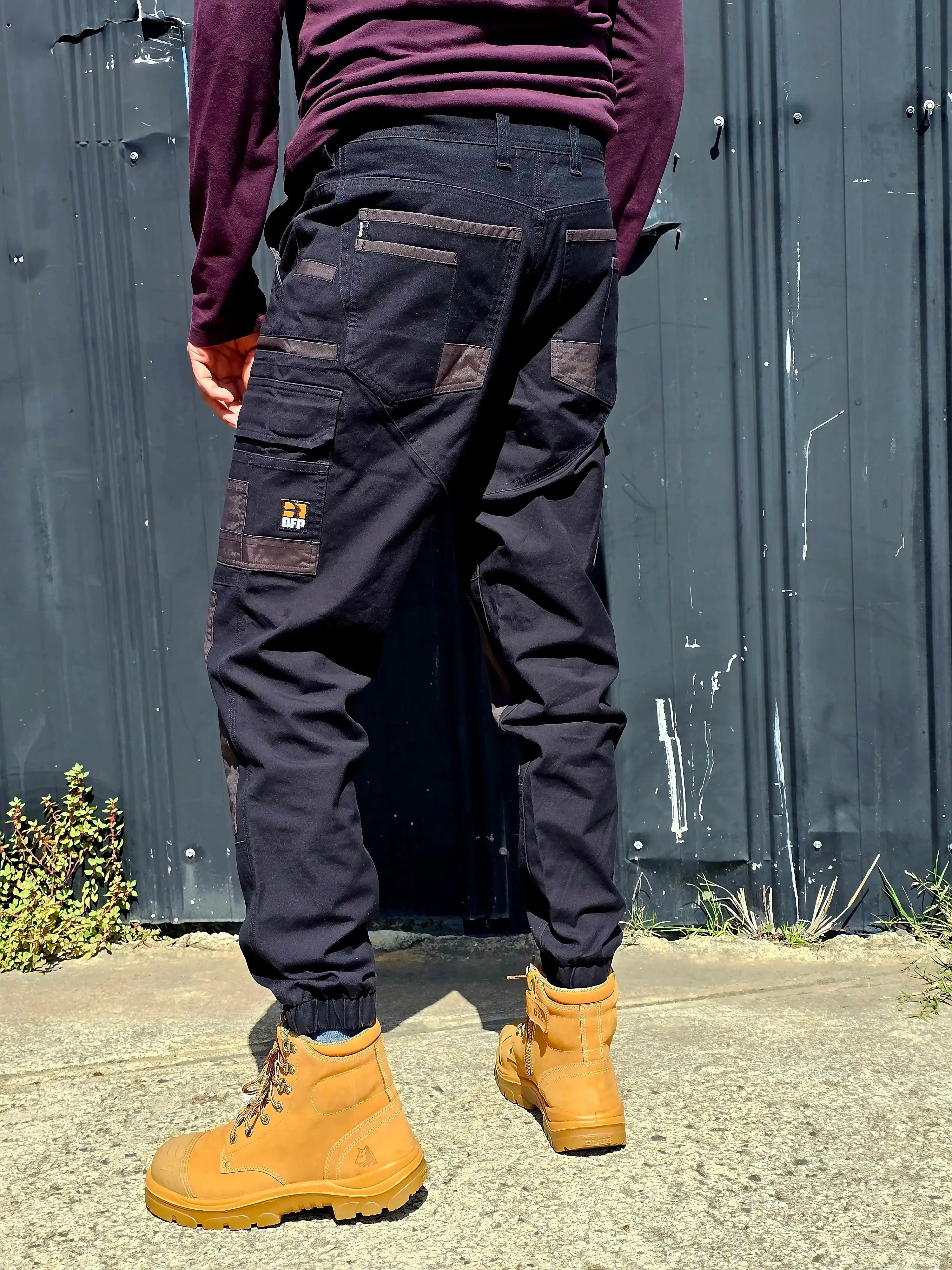 Tradie wearing DFP PP4 black work pants with tan boots on a worksite